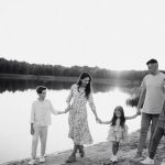 Monochrome photo of a family walking hand in hand along a serene lakeshore.